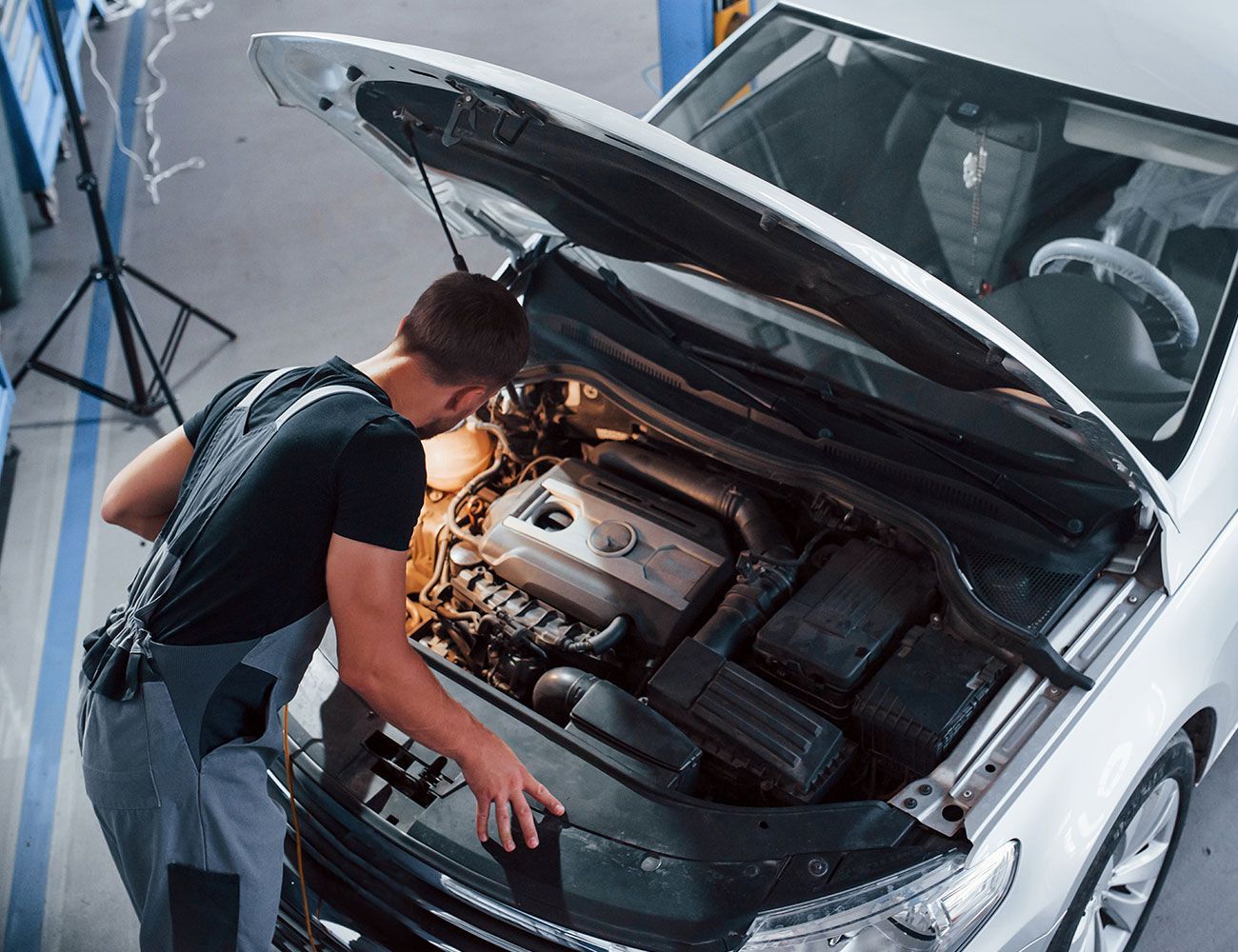 Ein Mann schaut in ein Motorraum eines silbernen Autos