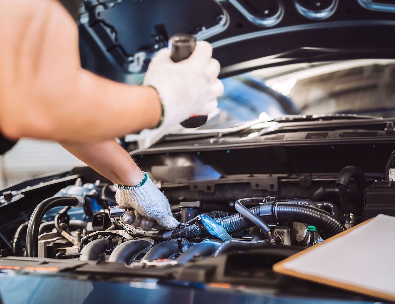 Ein Mann schaut mit einer Taschenlampe in der Hand in den Motorraum eines Autos